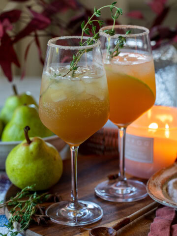 Refreshing pear cocktails with fresh herbs on a wooden serving board, perfect for summer drinks.