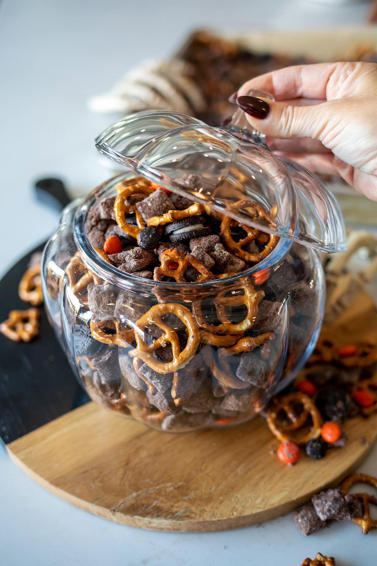 Halloween Muddy Buddies with chocolate-coated Rice Chex, mini pretzels, Mini Oreos, and orange and black M&M's party mix.