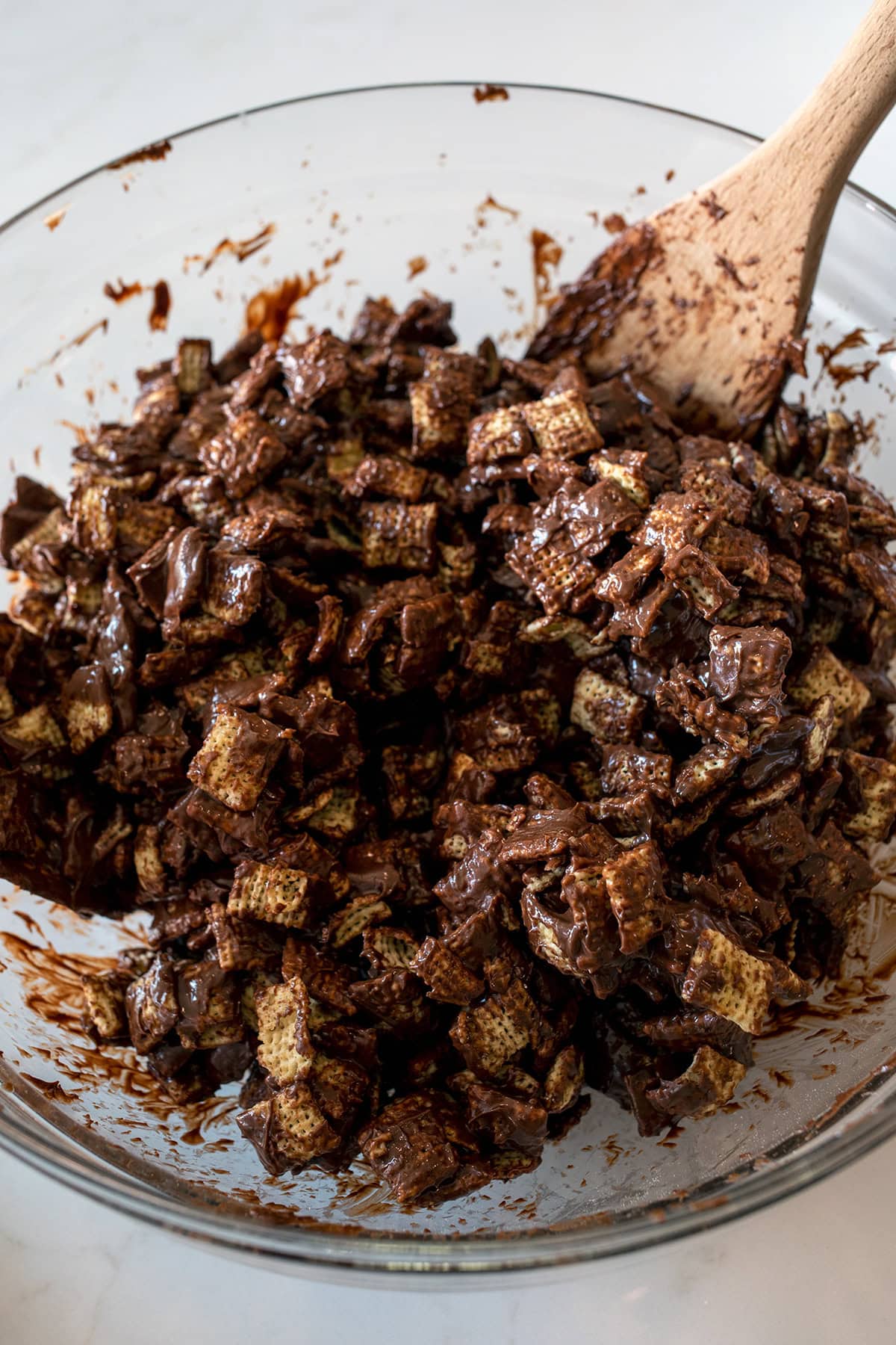 Melted Chocolate coated chex cereal in a glass bowl.