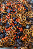 Halloween Muddy Buddies with chocolate-coated Rice Chex, mini pretzels, Mini Oreos, and orange and black M&M's party mix.